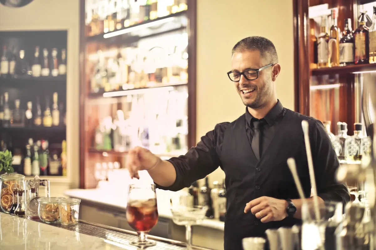 Bartender sonriendo mientras prepara un cóctel