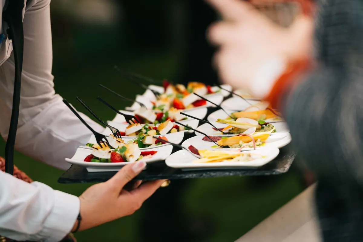 Mesonero sirviendo una bandeja de canapés a los invitados de un evento