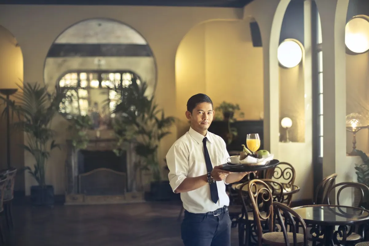Mesonero con bandeja de bebidas en un salón elegante